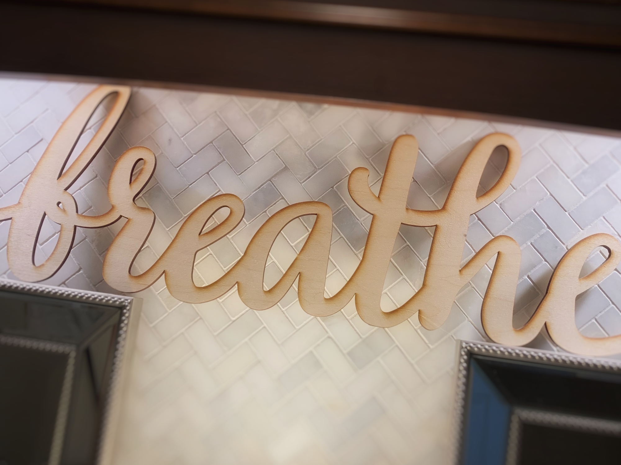 Wood cut sign that says "breathe" in script